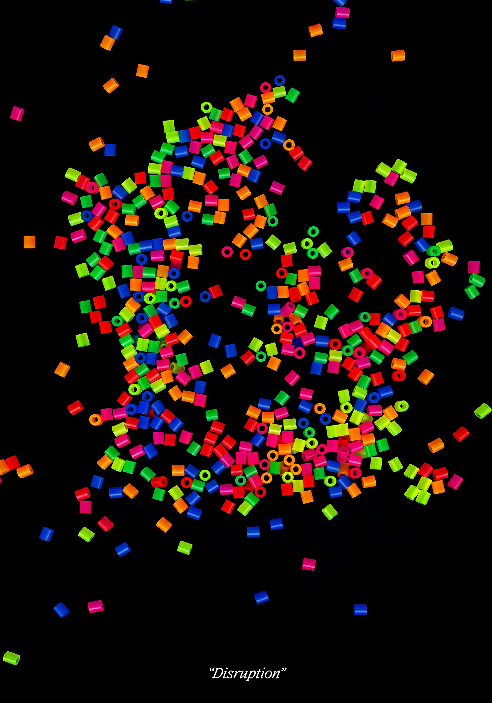 Neon fuse beads scattered in a loose burst across black, titled “Disruption”