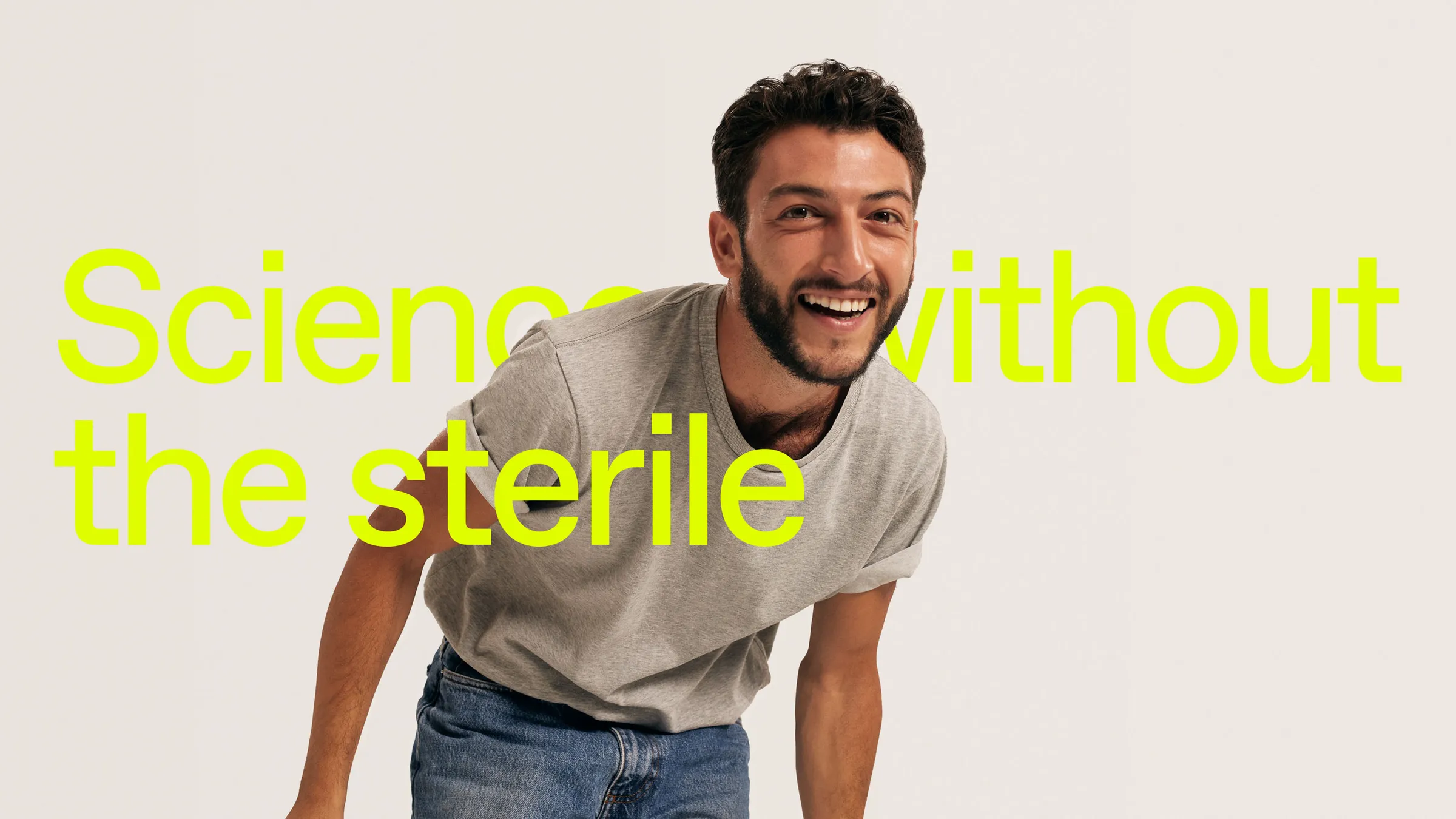 Smiling man in a grey T-shirt leaning forward behind the headline “Science without the sterile”