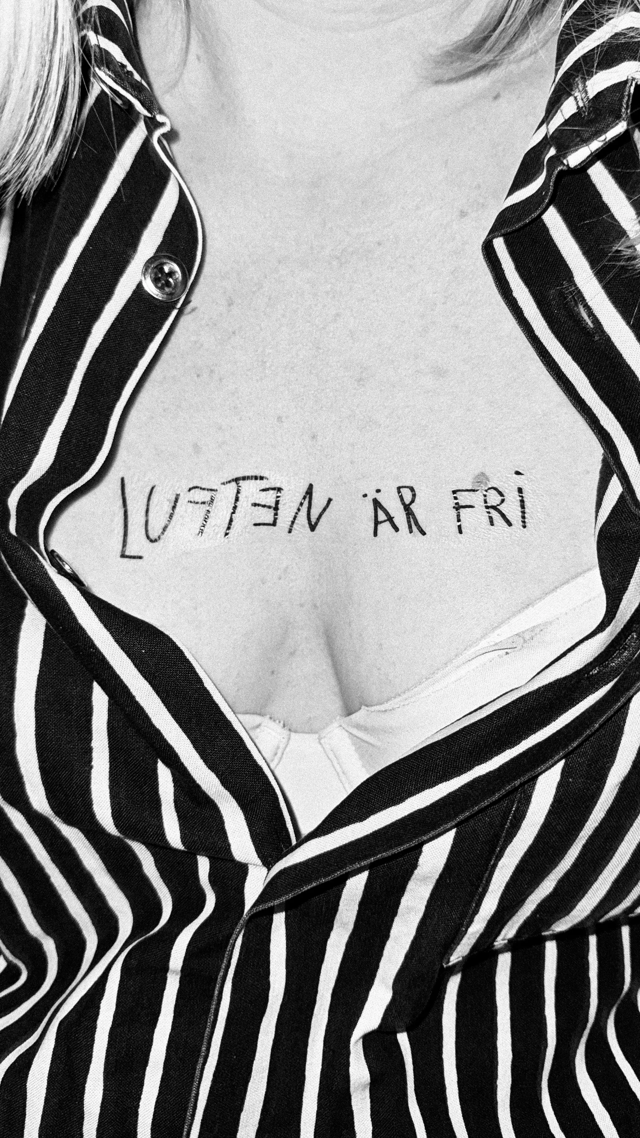 “Luften är fri” written across a chest framed by an open striped shirt